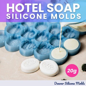 Pode incluir: Forma de silicone azul com 20 cavidades redondas individuais para fazer sabonetes de hotel. A forma está cheia de sabonete branco e um jarro despeja mais sabonete branco na forma. Uma barra de sabonete acabada é mostrada ao lado da forma. O texto "20g" é visível na imagem.