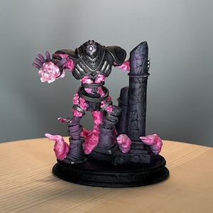 May include: A detailed figurine of a fantasy character with a dark gray armored upper body and pink, cloud-like lower body. The figure stands on a black base with a dark pillar behind it. The character's hand is outstretched, with a pink energy effect.