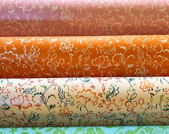 Puede incluir: Cinco rollos de papel de regalo estampado. Los rollos están apilados uno encima del otro. El rollo superior es rojo con un estampado floral blanco. El segundo rollo es rosa con un estampado floral blanco. El tercer rollo es naranja con un estampado floral blanco. El cuarto rollo es crema con un estampado floral multicolor. El rollo inferior es azul claro con un estampado floral verde.