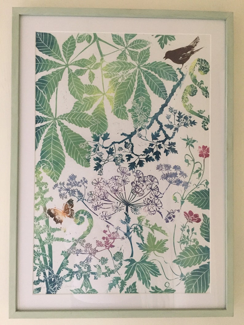 May include: A framed print of a botanical illustration featuring a variety of green leaves, flowers, and a butterfly. The print is on a white background and has a light green frame.