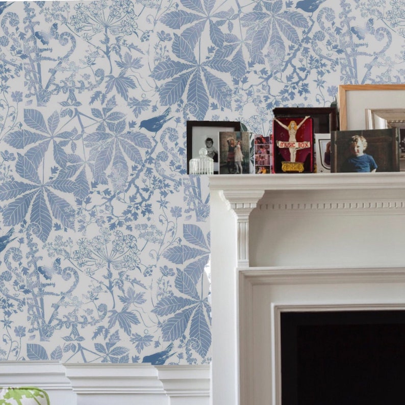 May include: A white fireplace mantel with a blue and white floral wallpaper background. The mantel is decorated with framed photos and a red book with the text "Music Box".