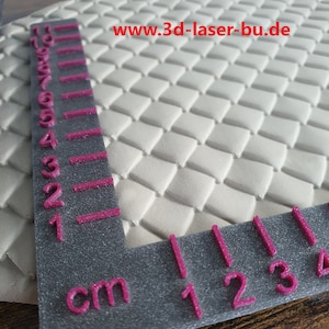 Könnte beinhalten: Nahaufnahme einer weißen, strukturierten Oberfläche mit einem Rautenmuster. Ein Lineal mit rosa Markierungen liegt auf der Oberfläche und zeigt die Maße in Zentimetern an. Der Text "www.3d-laser-bu.de" ist in der oberen rechten Ecke des Bildes sichtbar.