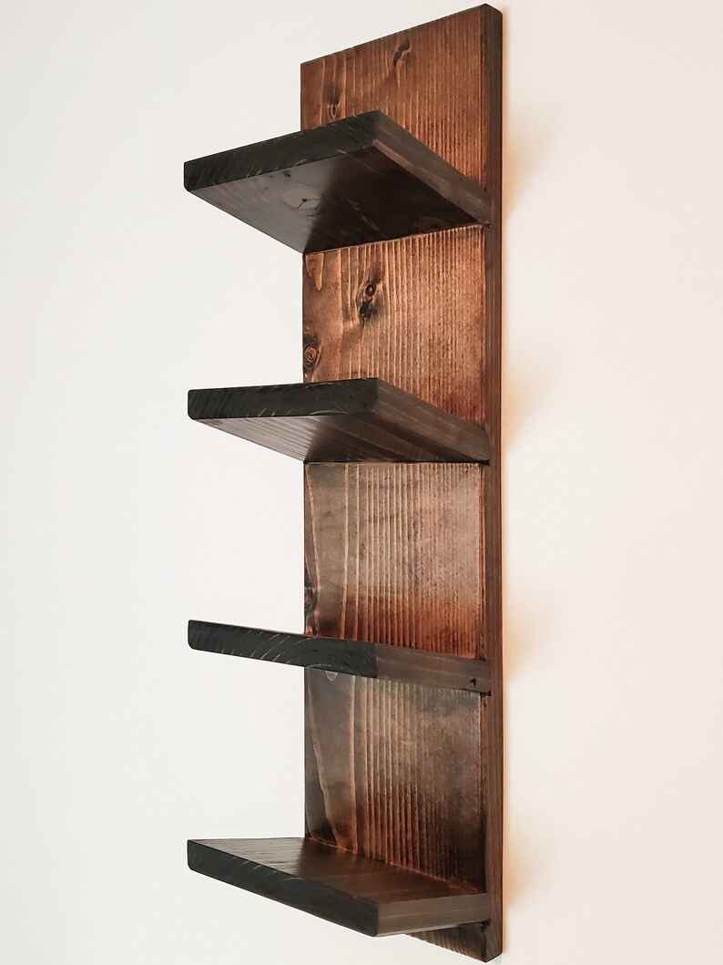 May include: A dark stained wooden wall shelf with four shelves. The shelves are square and project from a vertical backing. The wood grain is visible, and the finish is a deep brown with black edges. The shelf is designed for wall mounting.