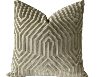 May include: A square throw pillow in a muted olive green tone featuring a raised, velvet-textured geometric pattern. The design consists of repeating, symmetrical chevron-like lines that create a structured, linear aesthetic across the surface.