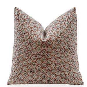 May include: A decorative throw pillow with a white background and a repeating pattern of brown and gray stylized Christmas trees.