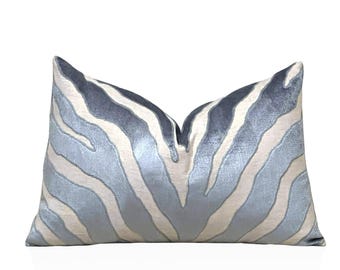 Può includere: Un cuscino decorativo con un motivo a zebre blu e bianco. Il cuscino è realizzato in un tessuto morbido e soffice.