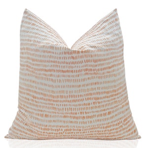 May include: A white throw pillow with a peach-colored abstract pattern of small dots.