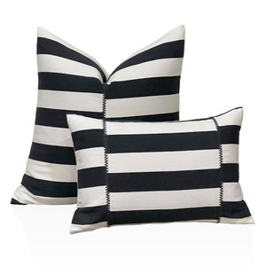 May include: Two cushions with a black and white striped design. The larger cushion is rectangular, and the smaller one is square. Both have a stitched seam detail.