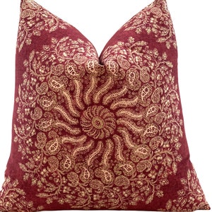 Könnte beinhalten: Ein rotes Kissen mit einem goldenen Mandala-Muster. Das Kissen ist aus einem weichen, strukturierten Stoff.
