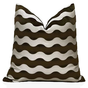 May include: A decorative throw pillow with a repeating wavy pattern in alternating shades of brown and white. The pillow is square and has a soft, textured appearance, suitable for home decor.