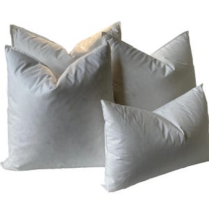 May include: Four white down pillows of different sizes, arranged in a pyramid shape.