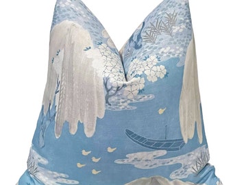 May include: A blue and white pillow with a Japanese-inspired design featuring mountains, cherry blossoms, and a boat. The pillow is made of a soft, linen-like fabric.
