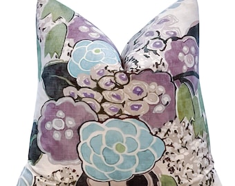 Può includere: Un cuscino decorativo con un motivo floreale con grandi fiori blu, viola e verdi su sfondo bianco.