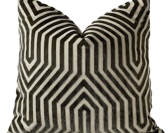 May include: A decorative pillow with a geometric pattern in shades of brown and beige. The pillow has a velvet-like texture and a geometric pattern of overlapping lines.