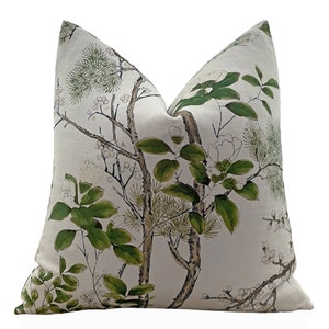 May include: A white pillow with a green floral pattern. The pattern features branches with leaves and flowers. The pillow is made of a soft, linen-like fabric.