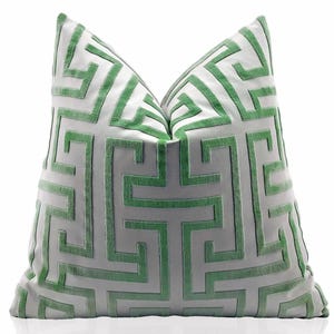 May include: A white pillow with a green geometric pattern. The pattern is a repeating design of interlocking squares and rectangles.