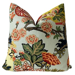 Puede incluir: Una almohada decorativa con un fondo azul claro y un estampado floral colorido. El estampado presenta flores y hojas rojas, naranjas, amarillas, verdes y azules. La almohada está hecha de una tela suave y texturizada.