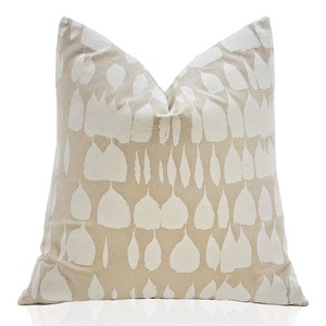 May include: A beige throw pillow with a white leaf pattern. The pillow is made of a soft, textured fabric.