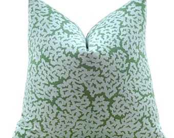 Può includere: Un cuscino verde e bianco con un motivo a barriera corallina. Il cuscino è realizzato in un tessuto morbido e confortevole ed è perfetto per aggiungere un tocco di stile costiero a qualsiasi stanza.