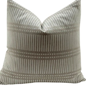 May include: A beige pillow with a white geometric pattern of vertical lines and dots.