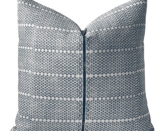 Puede incluir: Una almohada blanca con un patrón geométrico azul. La almohada tiene una cremallera y está hecha de una tela suave y cómoda.