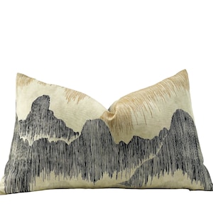 Pode incluir: Uma almofada retangular com fundo creme e um design de paisagem montanhosa preto e dourado.