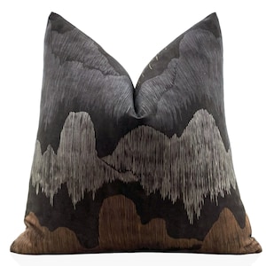 May include: A decorative throw pillow with a black background and a white and brown abstract design. The design features a series of vertical lines that create a textured effect.