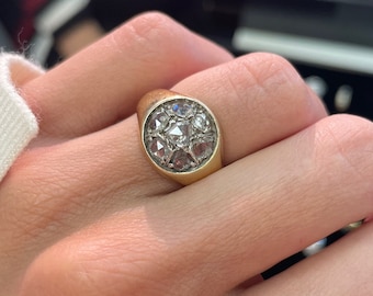 May include: A gold ring with a round bezel set with a cluster of small, clear diamonds.
