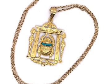 Puede incluir: Un collar de cadena de oro con un colgante que presenta un escarabajo en un marco de oro. El escarabajo tiene una incrustación de piedra turquesa.