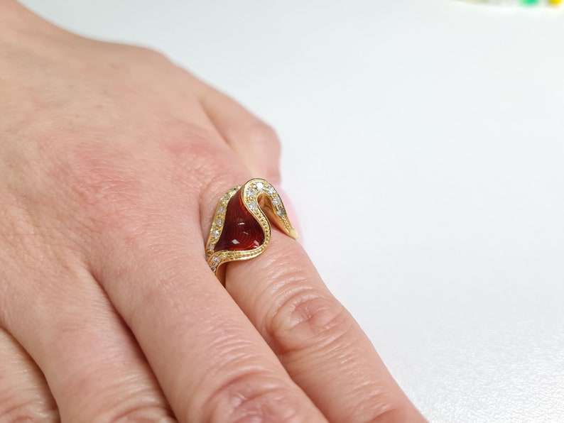 May include: A gold ring with a red stone and clear stones set in the band.