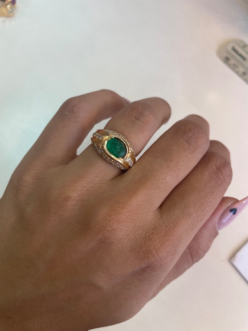 K&ouml;nnte beinhalten: Ein goldener Ring mit einem gro&szlig;en ovalen Smaragd, der von kleineren Diamanten umgeben ist.