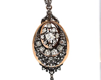 Puede incluir: Colgante antiguo con diseño ovalado y un grupo central de diamantes. El colgante tiene un marco dorado con filigrana de metal oscuro, pequeños diamantes y perlas. Una sola perla cuelga de la parte inferior. Mide unos 5 cm de largo.