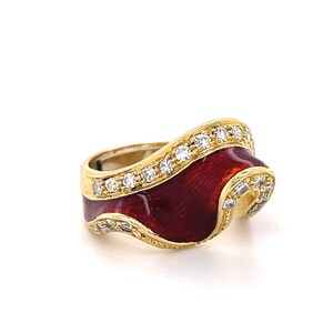 May include: A gold ring with a red enamel band and a row of clear diamonds. The band is shaped like a wave.