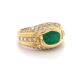 K&ouml;nnte beinhalten: Ein goldener Ring mit einem gro&szlig;en gr&uuml;nen Smaragd, der von kleineren Diamanten umgeben ist.