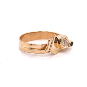 May include: A gold ring with a geometric design featuring a white gemstone and a black gemstone.