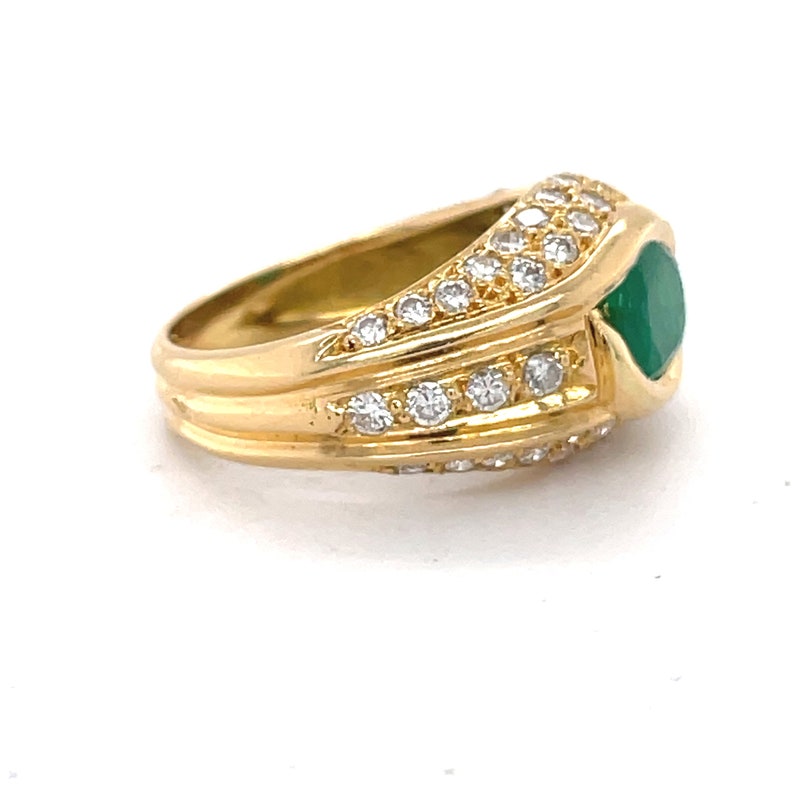 K&ouml;nnte beinhalten: Ein goldener Ring mit einem gr&uuml;nen Edelstein und einer Reihe von pav&eacute;-besetzten Diamanten.