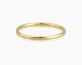 Puede incluir: Un brazalete fino de color dorado. El brazalete circular es liso y brillante, reflejando la luz. La joya está sobre un fondo blanco. Este diseño minimalista es adecuado para el uso diario.