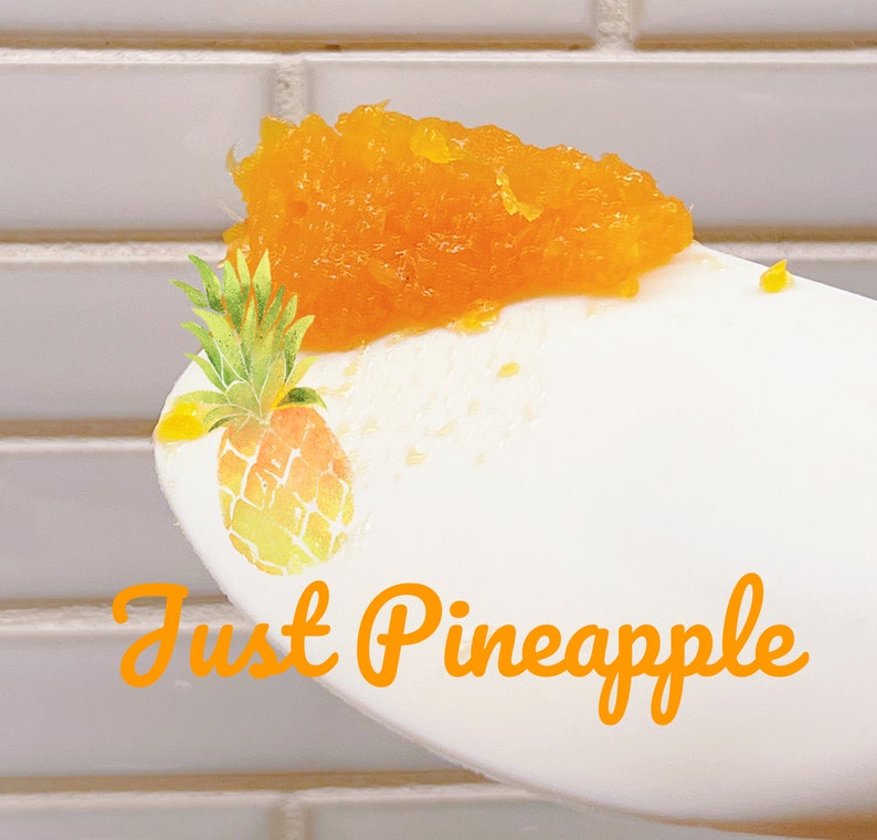 K&ouml;nnte beinhalten: Ein wei&szlig;er L&ouml;ffel mit einem H&auml;ufchen leuchtend orangefarbener Ananasmarmelade. Der L&ouml;ffel ist mit einer Aquarell-Illustration einer Ananas und dem orangefarbenen Schriftzug Just Pineapple auf dem Stiel versehen. Die Fruchtstruktur ist erkennbar.