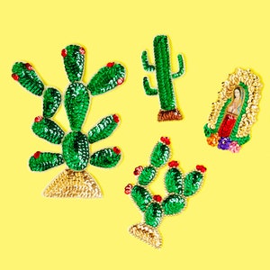 May include: Four decorative patches on a yellow background. The patches include three green sequined cactus designs with red accents and a sequined image of the Virgin Mary. The cactus designs have gold sequin bases.