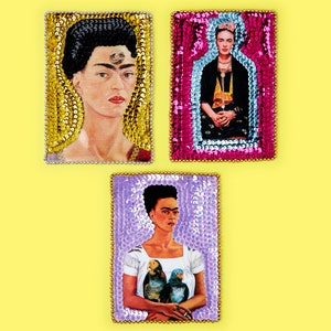May include: Three framed images of Frida Kahlo, each with a different background of colourful sequins. The first image shows Frida Kahlo with a unibrow and a flower in her hair. The second image shows Frida Kahlo in a bottle-shaped frame. The third image shows Frida Kahlo holding two parrots.