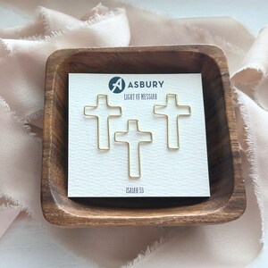 May include: Three gold cross-shaped paper clips on a white card with the text "Asbury Light of Messiah Isaiah 53".
