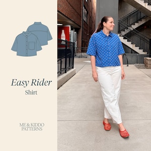 May include: A short-sleeved button-down shirt in blue with a repeating pink and white geometric pattern, featuring a collar, a front chest pocket, and a boxy fit. The text Easy Rider Shirt and ME & KIDDO PATTERNS is visible on the left side.