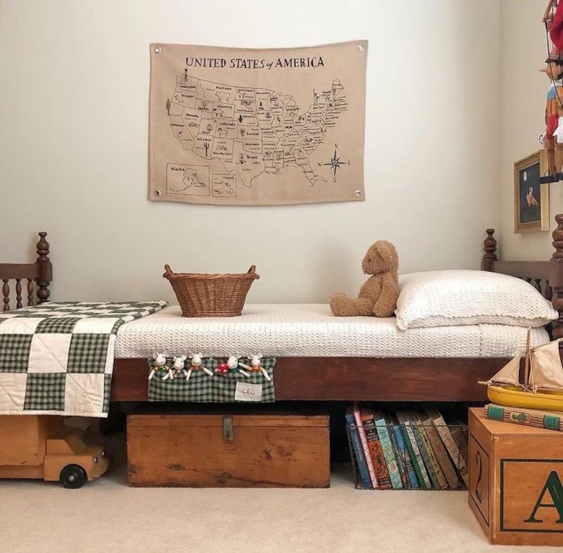 May include: A wooden bed with a green and white checkered quilt, a teddy bear, and a woven basket. The bed is decorated with a map of the United States that says "United States of America".