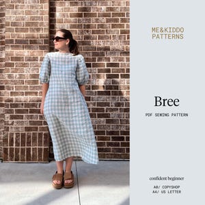 May include: A light blue and white gingham dress with short, puffy sleeves. The dress is knee-length and worn with brown sandals. The image includes the text "Bree PDF Sewing Pattern" and "ME&Kiddo Patterns".
