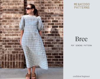 May include: A light blue and white gingham dress with short, puffed sleeves. The dress is knee-length and worn with brown sandals. The image includes the text "Bree PDF Sewing Pattern" and "ME&Kiddo Patterns".