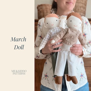 May include: Two handmade fabric dolls with embroidered facial features. One doll wears a light beige gingham shirt and dark green trousers. The other doll wears a textured tan knit sweater with bobble details and light grey striped trousers.
