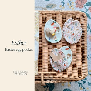 May include: Three egg-shaped fabric pockets featuring a white background with a gold lattice pattern, carrots, flowers, and small houses. Two pockets contain a small wooden chicken figure. Text on the left reads Esther Easter egg pocket ME & KIDDO PATTERNS.