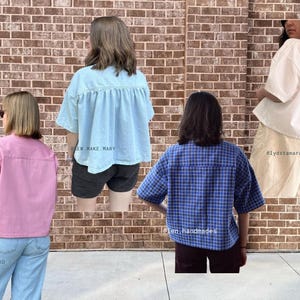 May include: Four different women's tops are shown against a brick wall. The tops are in pink, light blue, blue plaid, and white. The image displays a range of casual shirts, suitable for everyday wear. The tops are in various styles.