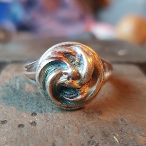 May include: A silver ring with a swirling, textured design. The ring is a unique piece of jewelry with a modern and abstract style.