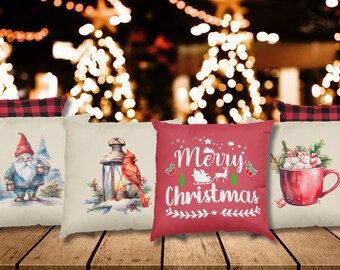 May include: Four decorative throw pillows with Christmas-themed designs. The pillows are arranged in a row on a wooden surface. The designs include a gnome holding a lantern, a cardinal perched on a lantern, a red mug with marshmallows and a candy cane, and a red pillow with the text "Merry Christmas" in white.